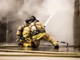 Two firefighters spraying water onto smoke located in a training burn room